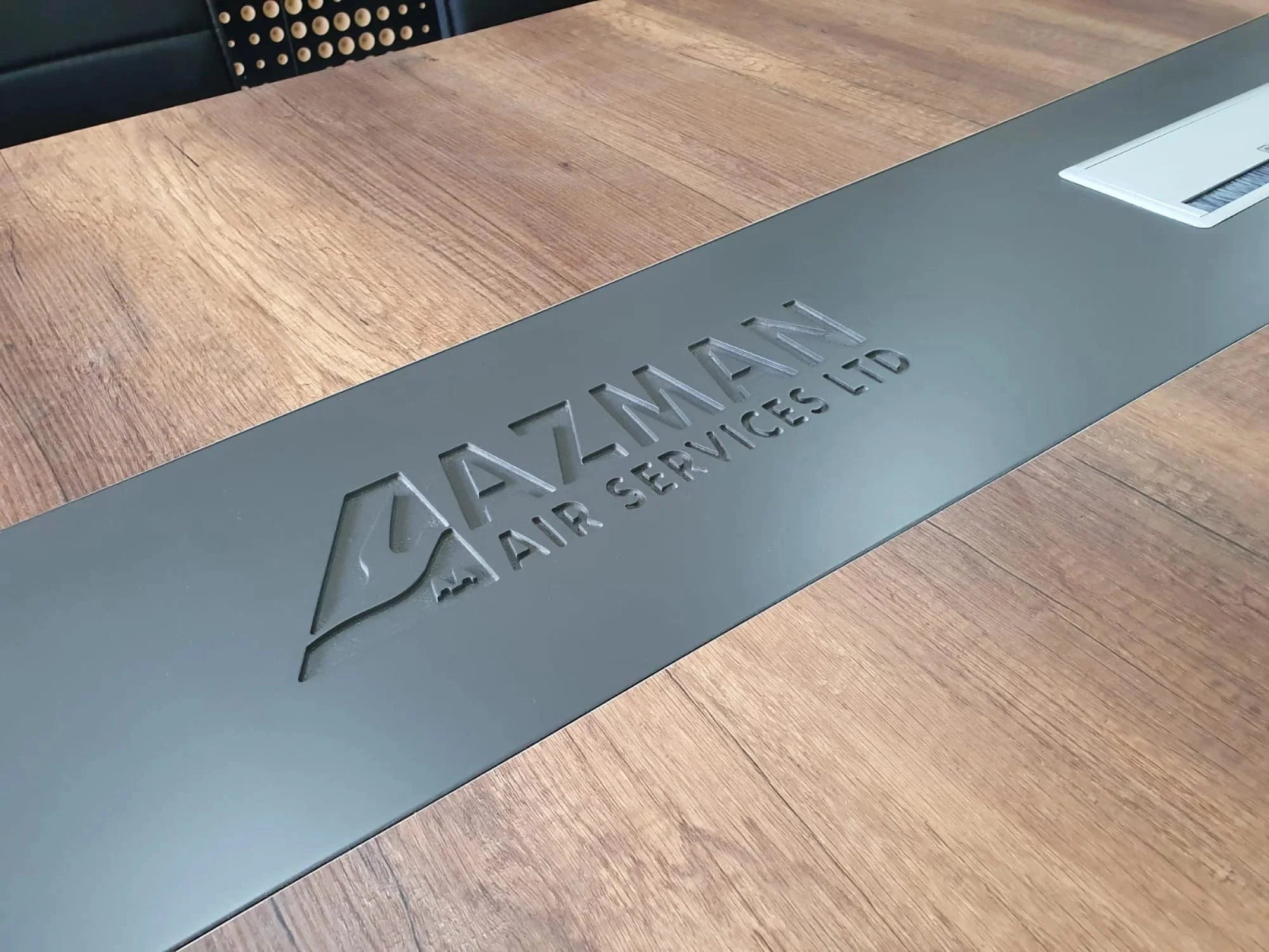 İstanbul Ofis Mobilya tasarımı, ceviz ahşap ve koyu gri detaylı, Azman Air logolu modern büyük ofis toplantı masası.